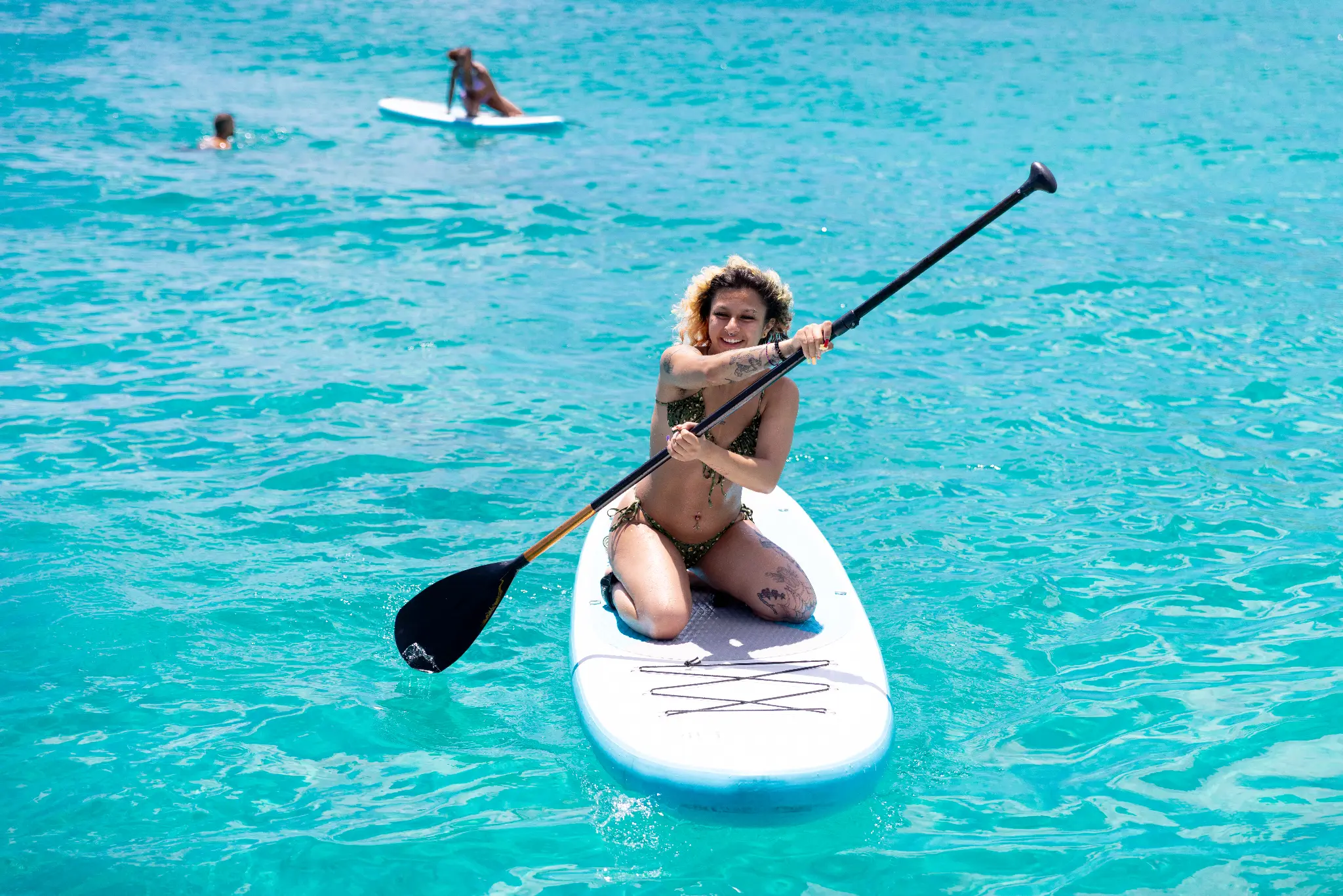 Guest paddleboarding on turquoise Caribbean water from The Phoenix catamaran