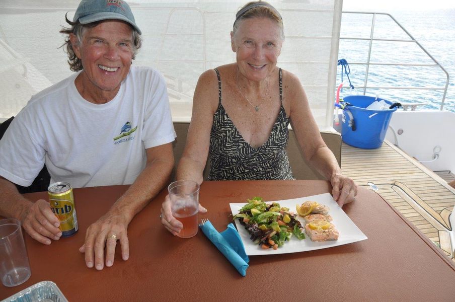 Two guests seated at a table aboard Sail The Phoenix smiling as they sip drinks