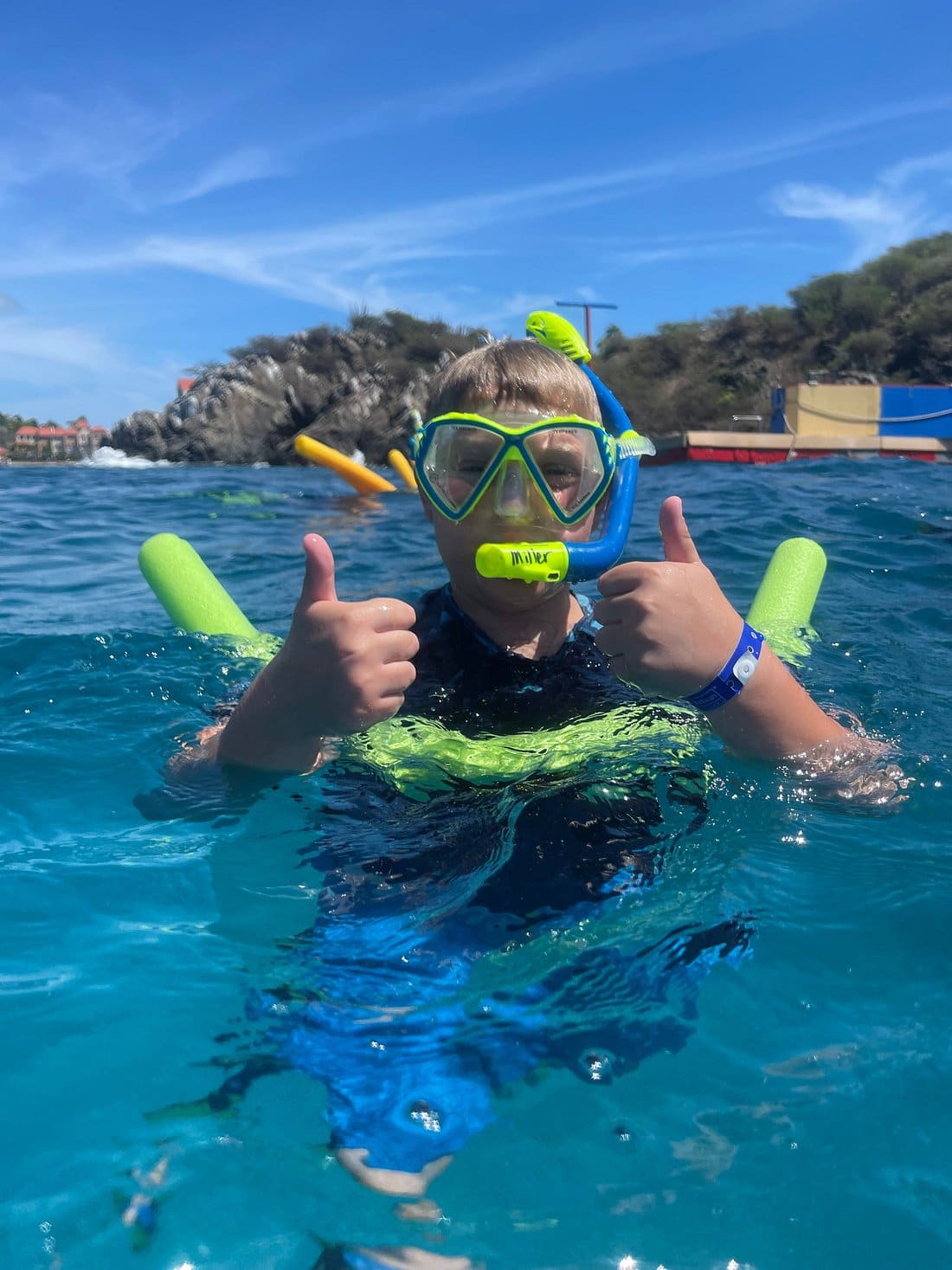 Child snorkeling at Little Bay with thumbs up, St. Maarten